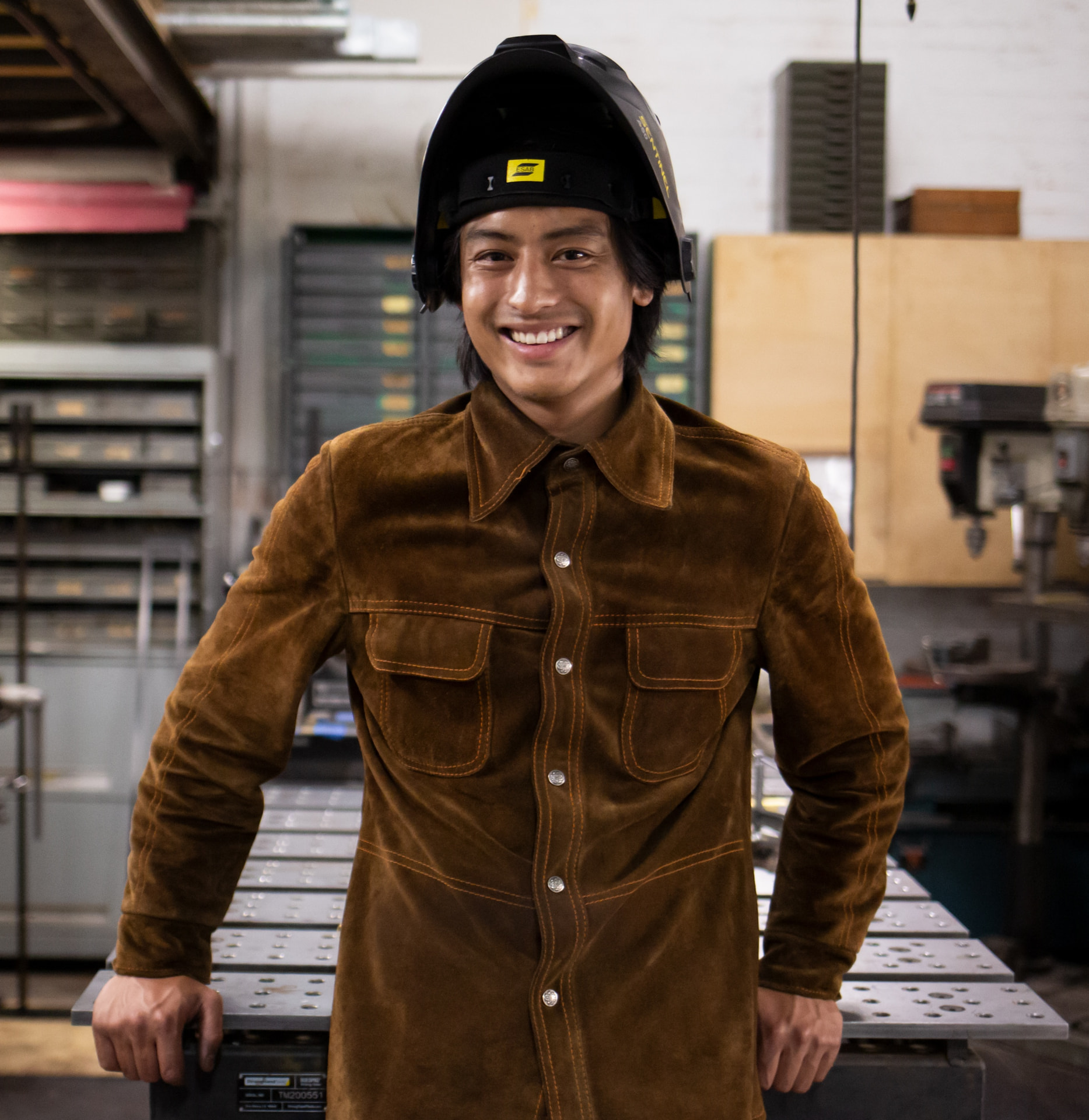 Evan Yee in his fabrication studio wearing a welding jacket