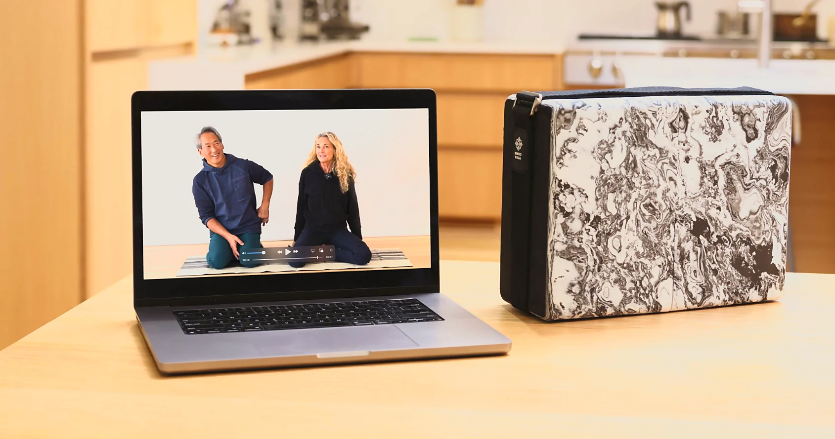 Rodney and Colleen Yee teaching on a laptop beside the Bento Yoga ONE kit on a kitchen counter