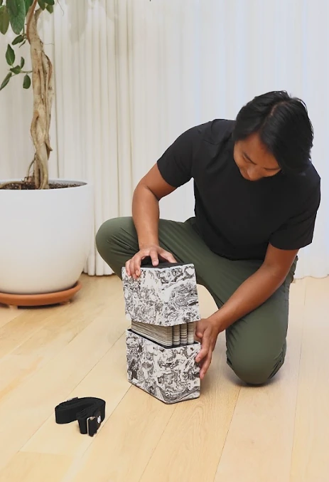 A practitioner packing the accordion-folded mat inside the Bento Yoga blocks